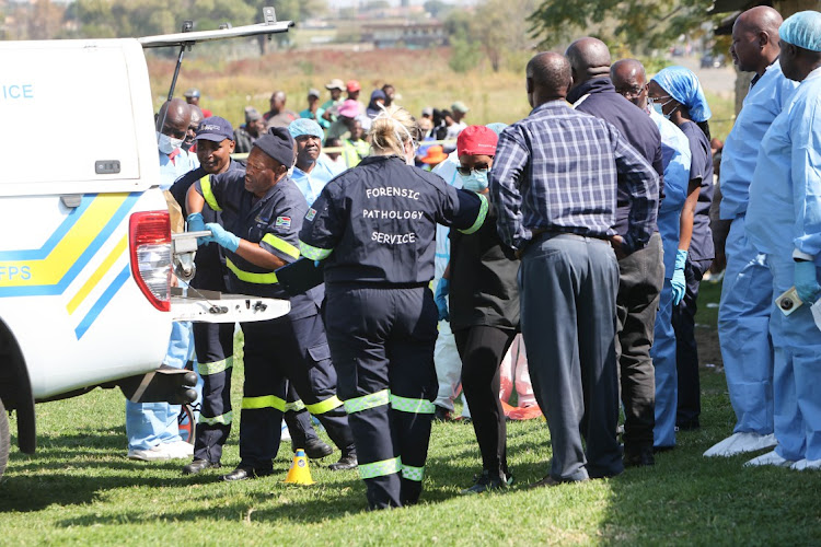 Forensic pathology members and police remove the body of a five-year-old boy in Rockville, Soweto, on Thursday morning. His body and that of another boy, aged six, were found mutilated after they went missing the day before.