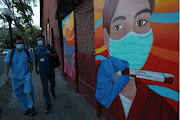 Health workers walk past paintings placed as a sign of gratitude by neighbors to health workers at a hospitals area, during the coronavirus disease outbreak in Santiago, Chile on March 9 2021.
