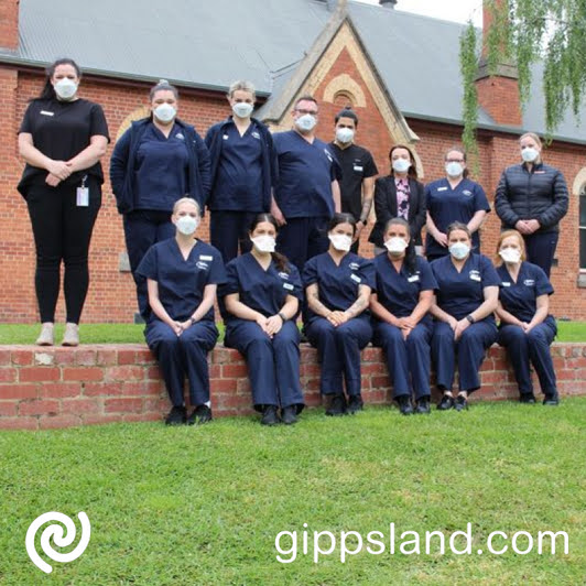 A group of 14 nurses and Bendigo Health staff gather in front of a brick building