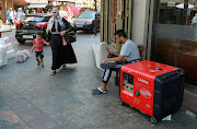 A woman with a child walk past a portable generator, which provides electricity, in Sidon, Lebanon, August 11, 2021. 