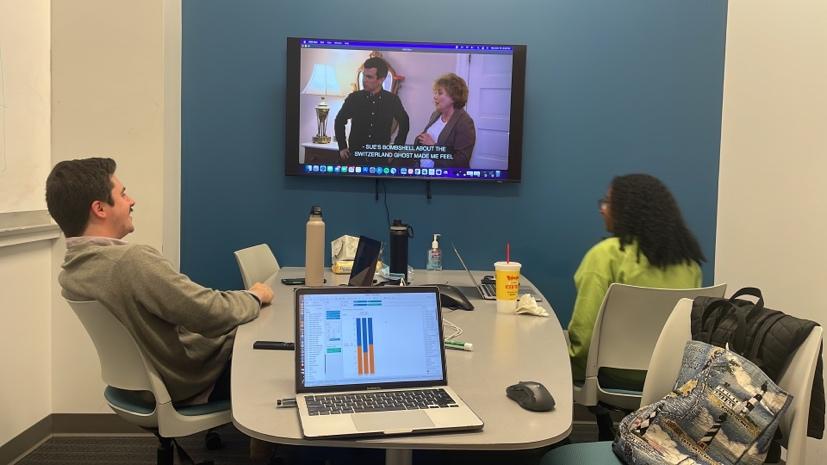 A person and person sitting at a table watching a television

Description automatically generated with low confidence