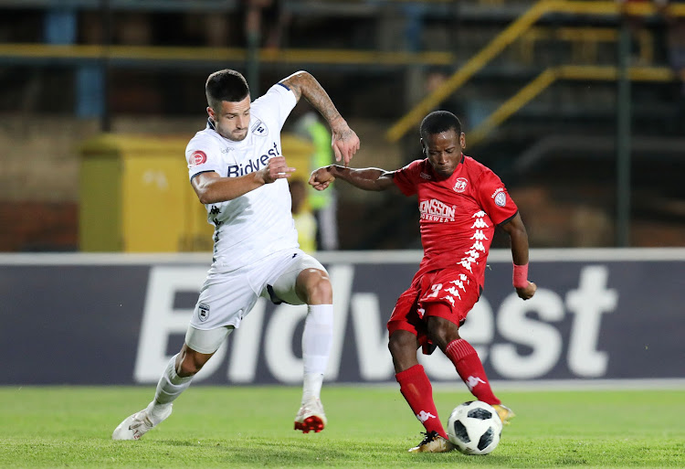 Highlands Park midfielder Lindokuhle Mbatha attempts a shot at goal as his Bidvest Wits counterpart Keegan Ritchie tries to block his shot during the Absa Premiership match at the Bidvest Stadium in Johannesburg on October 26, 2018.