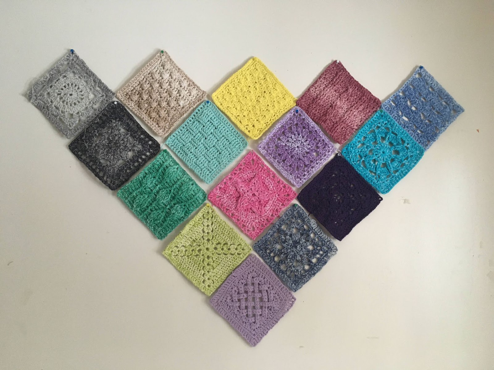 Fifteen colorful crocheted squares arranged in a diamond pattern.