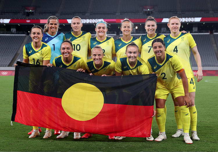 Australia players pose with the Australian Aboriginal flag for a team group photo before the match.