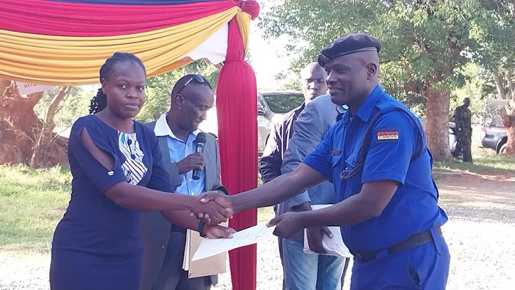 Eastern NTSA regional manager Roseline Oloo presents a gift to a police officer gifted by Machakos county police commander Issa Mohammud for appreciation for good work at County police headquarters on January 13, 2023.