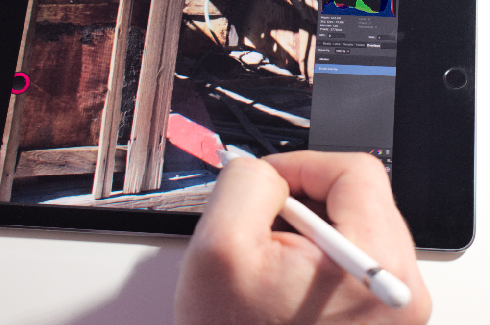 A person touches up the corner of a photo in photoshop using a pen. 