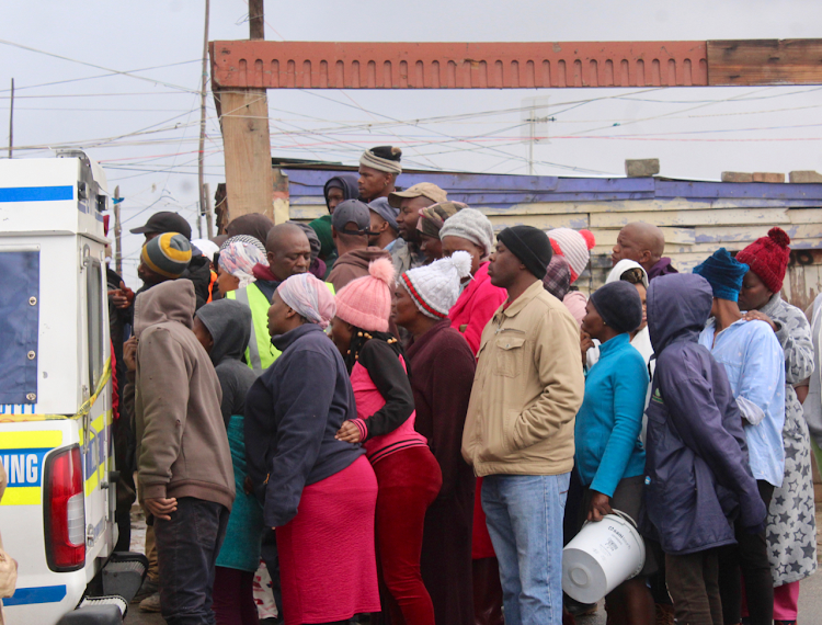 Onlookers gather after a man in New Village , Nomzamo, was electrocuted while trying to restore power to some shacks in the area.