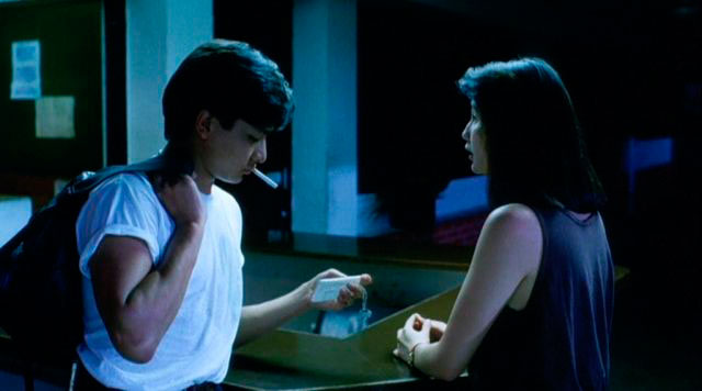 This is a screen still from As Tears Go By. A man and a woman stand facing each other, while a cigarette hangs out of the man's lips.