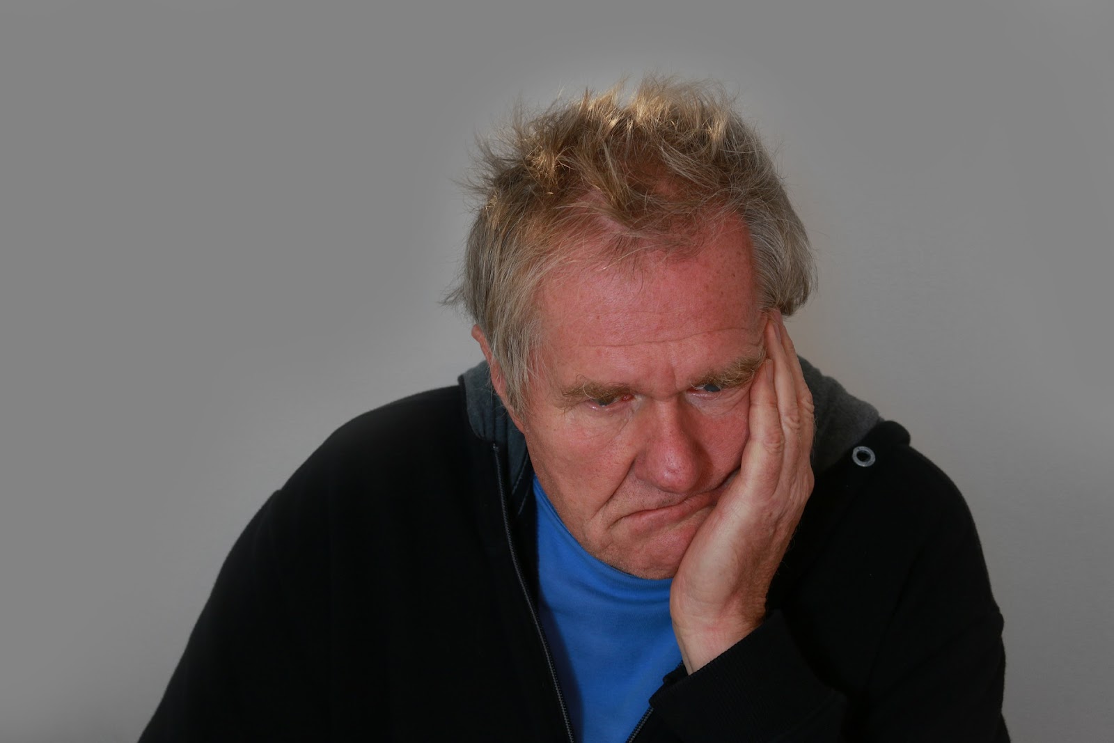 A middle aged man with his head resting on his hand, looking disappointed but not devastated