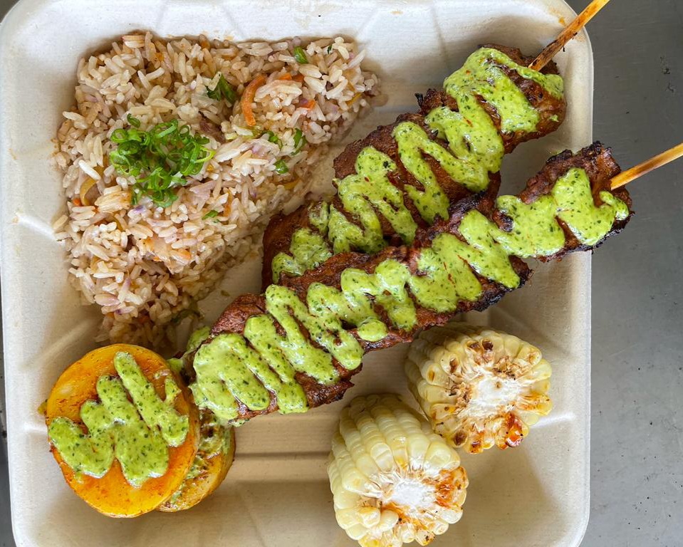 Anticuchos - Marinated beef skewers served with fried rice, potatoes, grilled corn, and huacatay sauce (Peruvian mint and herb sauce). Gluten Free.