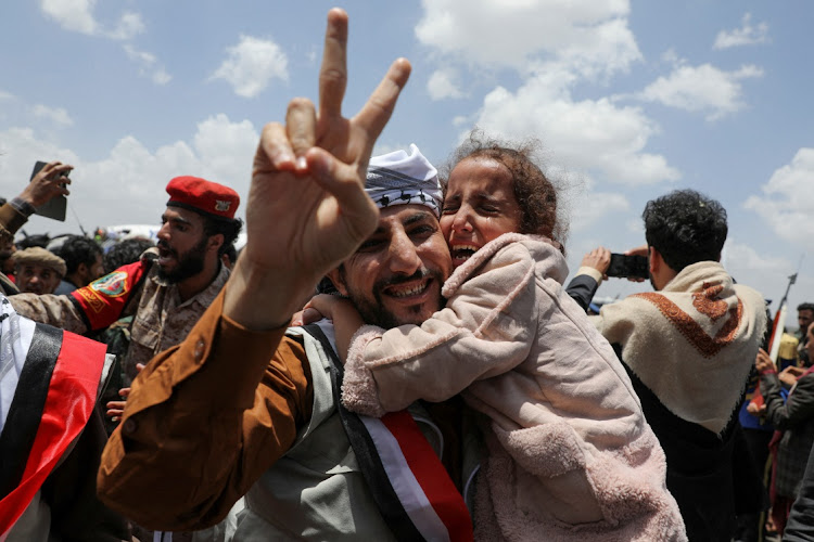 A freed prisoner gestures while holding a child after arriving at Sanaa Airport on an International Committee of the Red Cross (ICRC)-chartered plane in Sanaa, Yemen, on Friday. Picture: REUTERS/KHALED ABDULLAH