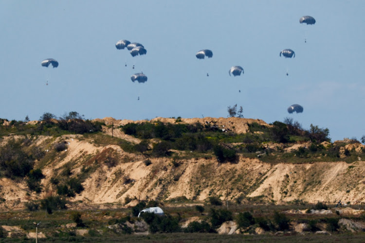 Packages fall towards northern Gaza, after being dropped from an Egyptian military aircraft, as seen from Israel’s southern border on March 10. Picture: REUTERS/AMIR COHEN