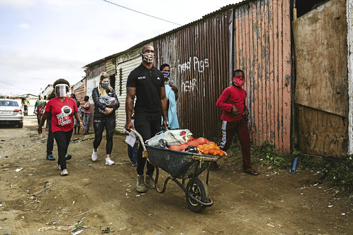 Siya and Rachel Kolisi use a wheelbarrow to deliver food in an East London township as part of their foundation's efforts to ease the plight of the poor.