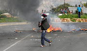 ON THE PROWL: A protester has a petrol bomb at the ready during clashes with riot police in Hout Bay.