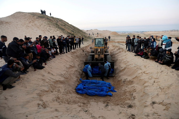 People bury Palestinians, who were killed by Israeli strikes and fire, after their bodies were released by Israel, amid the ongoing conflict between Israel and the Palestinian Islamist group Hamas, at a mass grave in Rafah, in the southern Gaza Strip on December 26 2023. Picture: REUTERS/IBRAHEEM ABU MUSTAFA