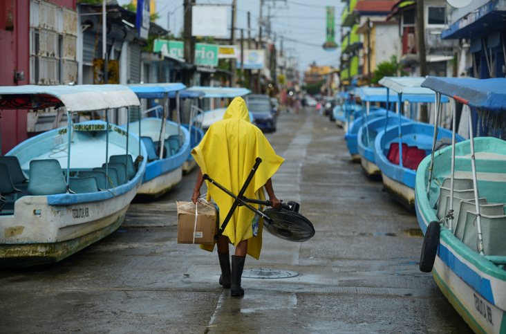 A man carries a fan and a box while walking past tourist boats that were moved from the water for safety as Hurricane Grace gathered more strength before reaching land, in Tecolutla, Mexico on August 20 2021.