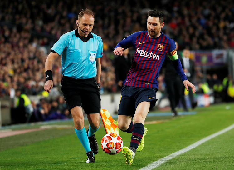 Barcelona's Lionel Messi tries to keep the ball in play as a match official looks on.