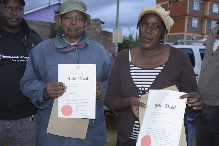 Umoja residents Ng'ang'a Njoroge and Phyllis Nyamweru display the title deeds they received on Tuesday after waiting for more than three decades.