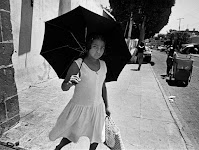 meisje in witte jurk met zwarte parasol op straat