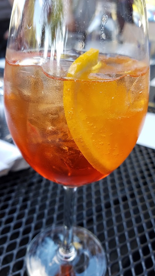 Aperol Spritz with Aperol, Sparkling Wine, and orange wheel, one of six curated cocktails offered at Ken's Artisan Pizza