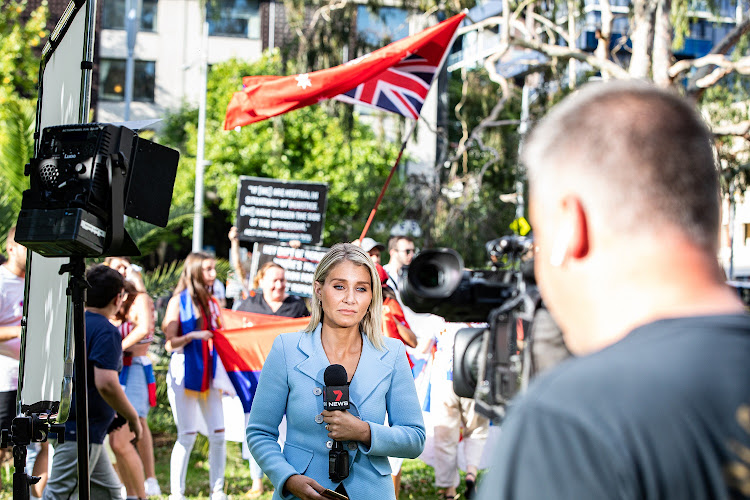 A Channel Seven reporter is seen going live as Novak Djokovic supporters rally outside Park Hotel in Melbourne on January 6 2022. Djokovic arrived in Melbourne to play in the upcoming Australian Open and was denied entry to Australia due to questions over the validity of his visa.