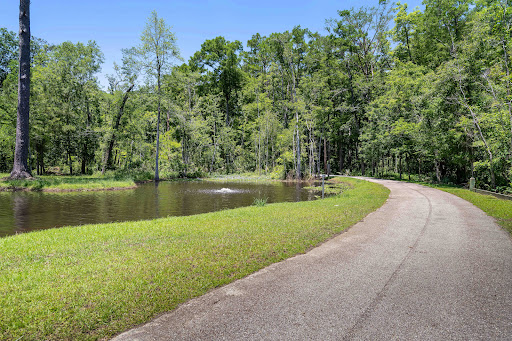Paved path bordering a wooded pond in this luxury land for sale in Mandeville ($112,500 - 809 m²)