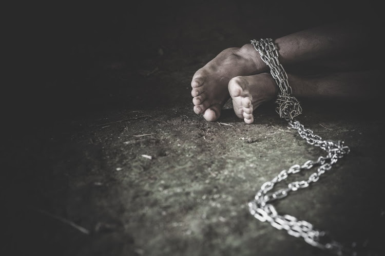 Hopeless man foot tied together with chain, Victims of human trafficking