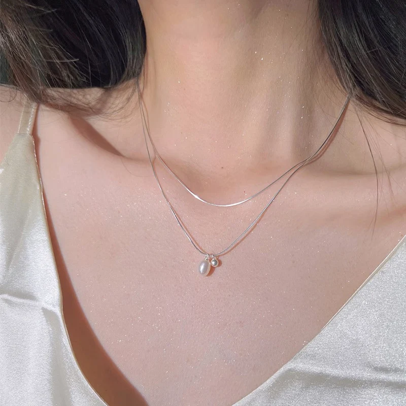 Minimalistische dubbellaagse ketting met natuurlijke parels, dubbele laag, hoogwaardige sluiting en een minimalistische, elegante uitstraling.