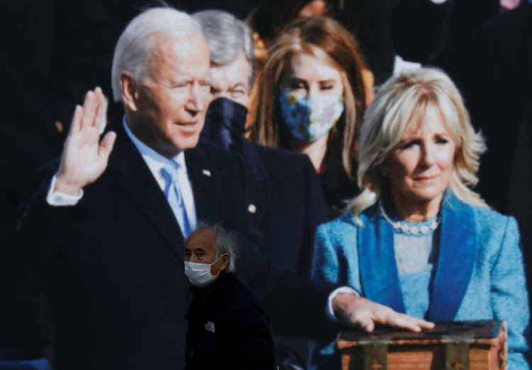 A man wearing a protective mask, amid the coronavirus disease (COVID-19) outbreak, walks past a large screen showing the news about inauguration of US President Joe Biden in Tokyo, Japa, on January 21, 2021. Picture: REUTERS/KIM KYUNG-HOON