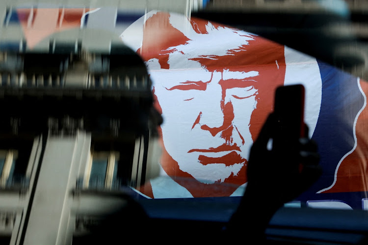 A person uses a smartphone with an image of former US president Donald Trump in the background in New York City on April 3 2023.