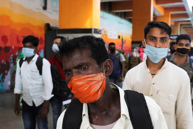 Passengers wearing protective face masks stand in a queue on a platform to get tested for Covid-19, at a railway station, in New Delhi, India, on October 5, 2020.