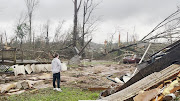 A man looks at damage and debris in the aftermath of a tornado in Centreville, Alabama, on March 25 2021 in this image obtained from a social media video. 