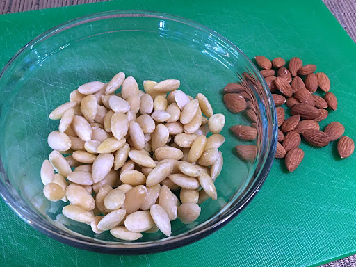 Blanched almonds in a bowl next to skin-on almonds.