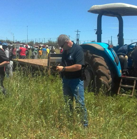 People gathering at the scene where a farm worker was allegedly killed for driving a stolen tractor.