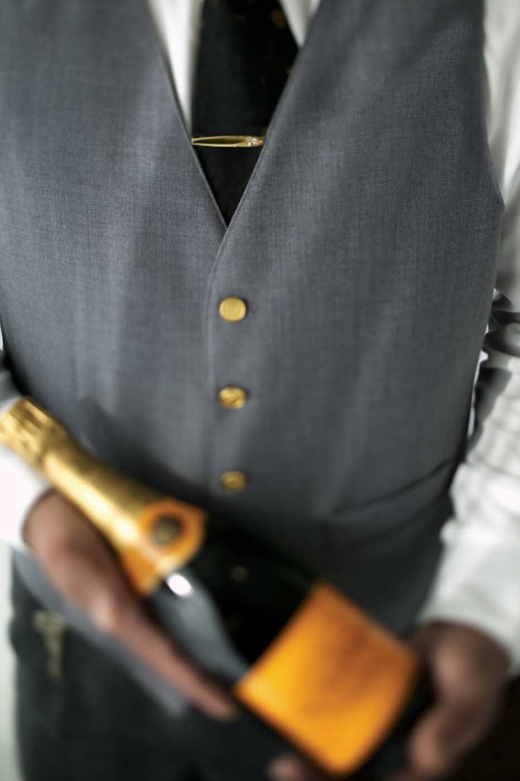 A butler handles a bottle of Champagne on a Regent Seven Seas cruise. 