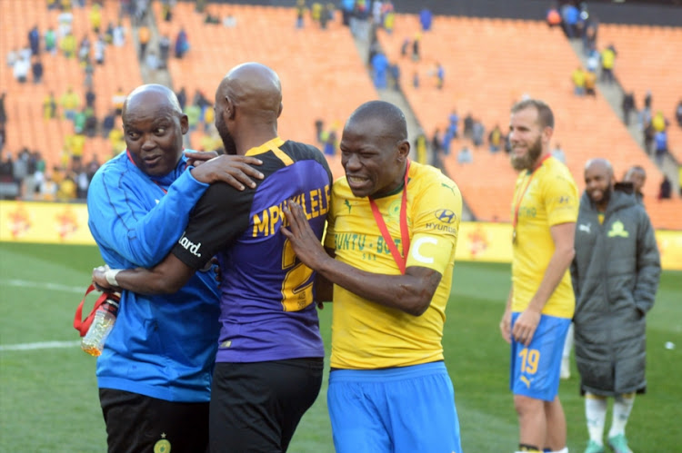 Mamelodi Sundowns head coach Pitso Mosimane hugs former player Ramahlwe Mphahlele, formerly with Sundowns, and captain Hlompho Kekana during the Shell Helix Ultra Cup match at FNB Stadium on July 21, 2018 in Johannesburg, South Africa.