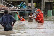 Members of the Civil Defence help a woman in a flooded street after the passage of Storm Laura, in Azua, Dominican Republic August 23, 2020. 