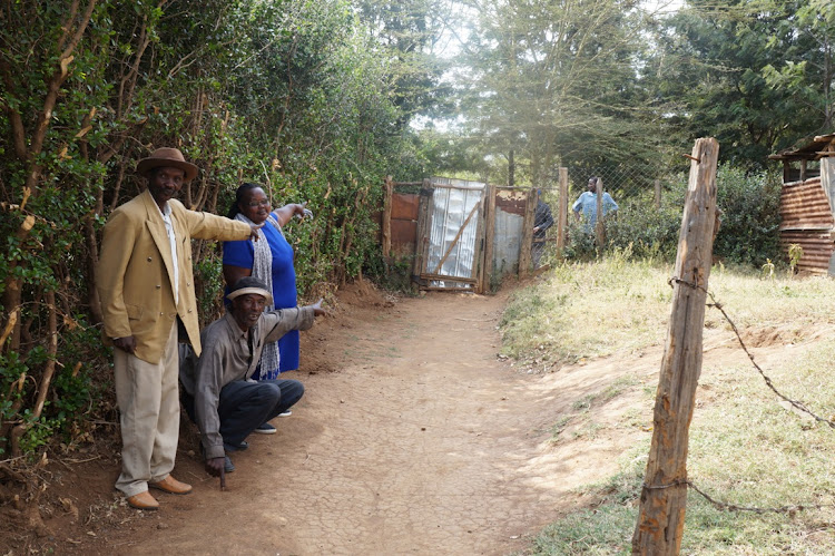 Resident David Ng'ang'a (center) shows his neighbours where a bacon was mounted, and where the road will start and extend outside his gate in Old Kijabe Town in Maai Mahiu.