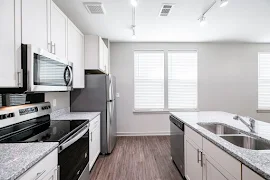 Kitchen with white shaker cabinets, brushed nickel hardware, stainless steel appliances, and gray speckled stone countertops