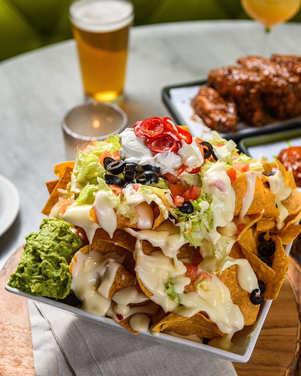 deluxe cheese nachos | 
lots of sharp white cheddar cheese sauce | pickled
fresnos | freshly squished guac | smoked salsa verde |
sour cream | shredded lettuce | tomato | sliced black olives