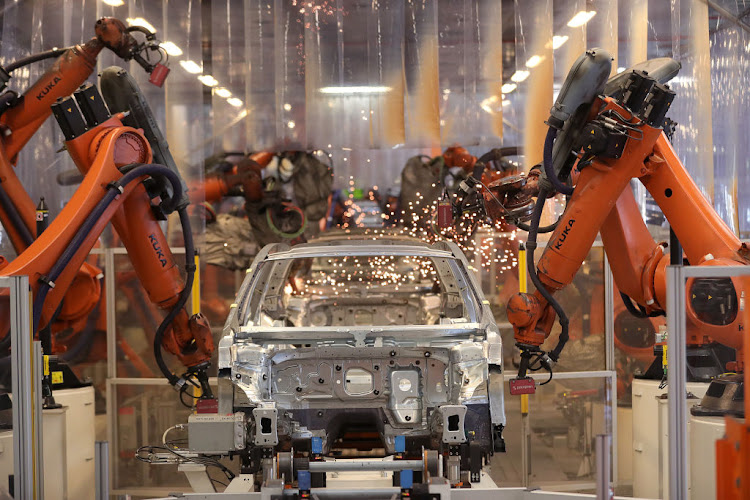 Robotic arms manufactured by Kuka AG operate on a Volkswagen Passat saloon chassis on the automated welding production line inside the VW factory in Emden, Germany.