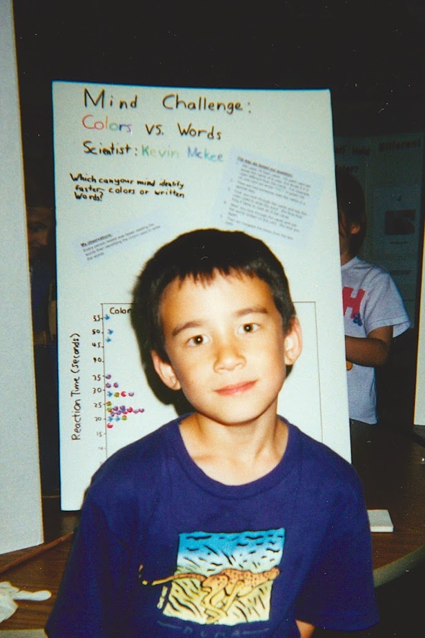 Kevin McKee as a child. He is standing in front of a whiteboard where he has plotted findings from an experiment.