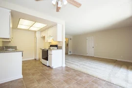 Dining room facing kitchen and living room, with rust-colored square tile flooring and a ceiling fan