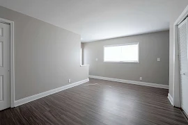 Living room with wood-style floors, neutral walls and a window with blinds