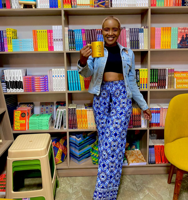 A girl wearing blue printed palazzo pants, black cropped top, and a denim jacket.