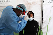 Health workers wearing personal protective gear perform mouth swabs for the testing of Covid-19 in Lenasia, south of Johannesburg on April 8.