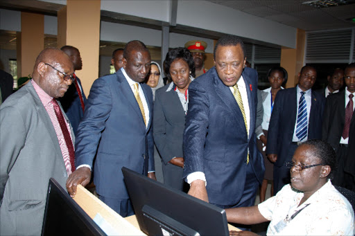 TECHNOLOGY: President Uhuru Kenyatta, Deputy President William Ruto and suspended Cabinet Secretary for Lands , Housing and Urban Development Charity Ngilu are shown the digitized maps of land by Cartographer Sarah Auma when they visited the National Titling Centre at the Kenya Institute of Survey and Mapping in July last year. PHOTO/FILE. PSCU