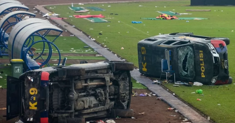 Damaged police vehicles lay on the pitch inside Kanjuruhan stadium