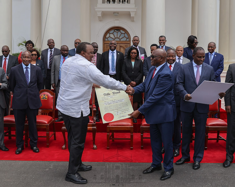 President Uhuru Kenyatta handing over the recovered title deed of a formerly corruptly acquired land.