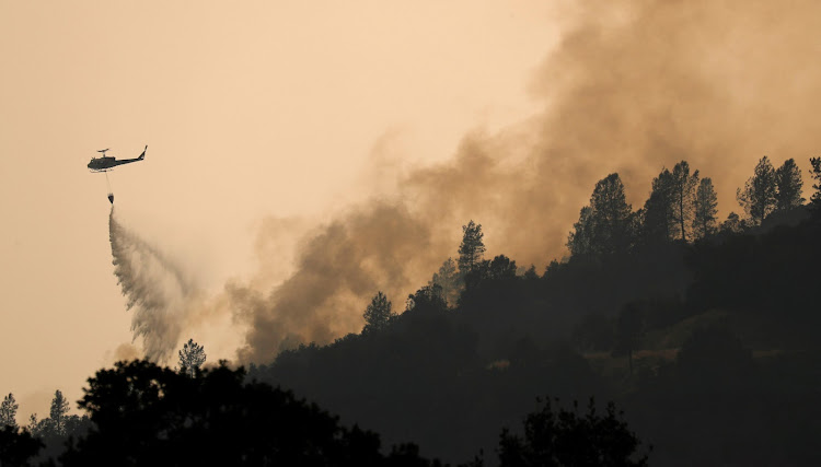 A helicopter drops water on hotspots of the Carr Fire burning in the hills west of Redding, California, U.S. July 27, 2018.